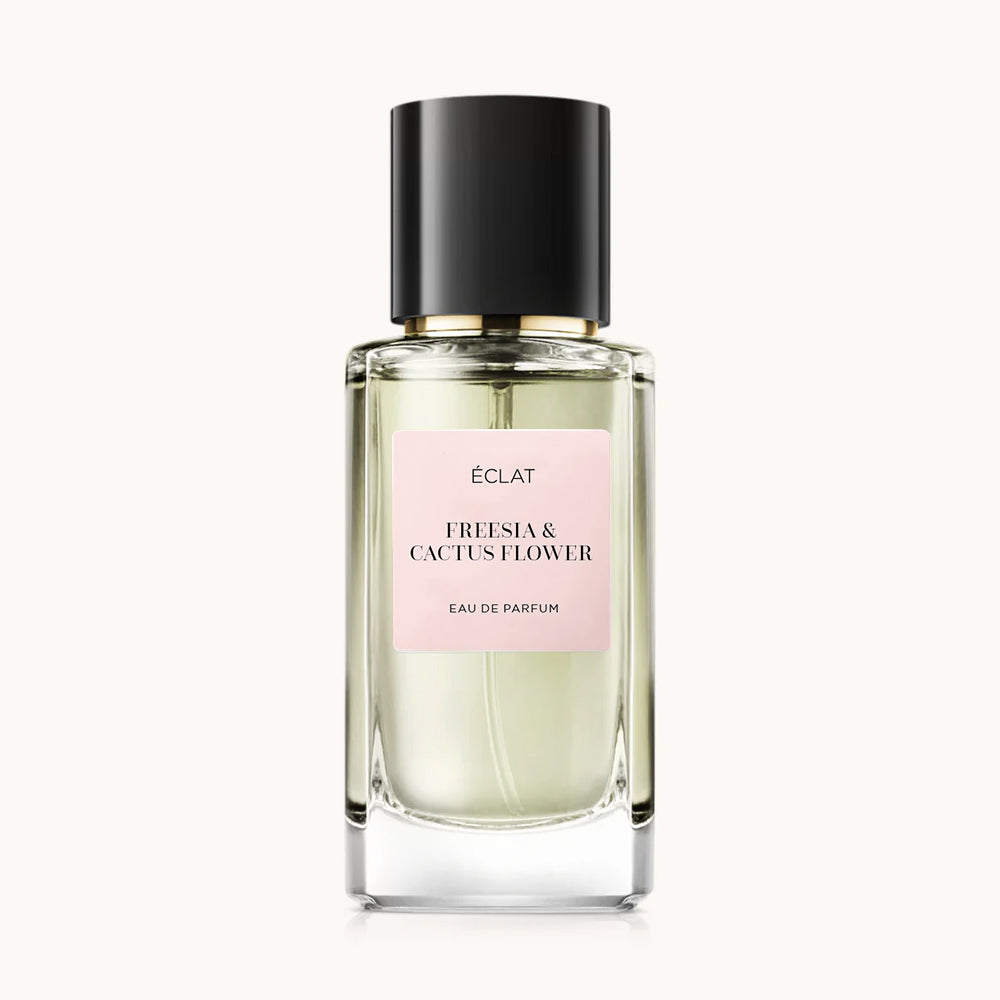 Flacon of the women’s perfume dupe ÉCLAT Freesia & Cactus Flower, an elegant transparent glass bottle with a black cylindrical magnetic cap and a light pink label. The label displays the brand name ÉCLAT, the name Freesia & Cactus Flower, and the phrase “Eau de Parfum”.