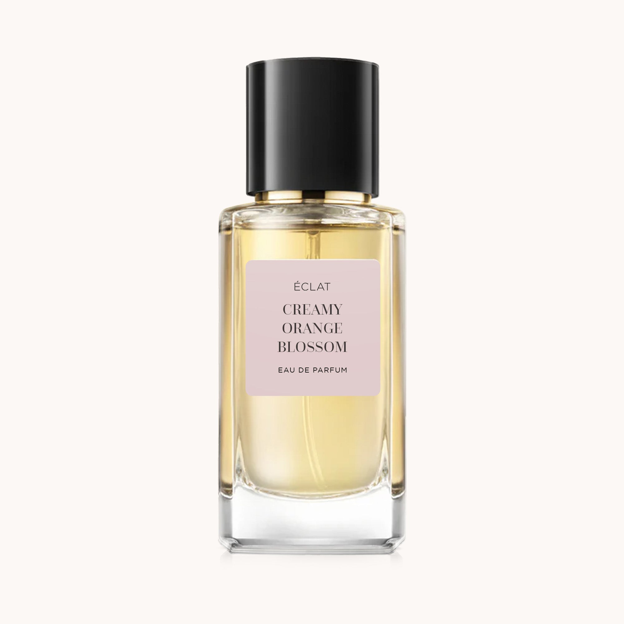 Der ÉCLAT Creamy Orange Blossom Parfumflakon zeigt ein facettiertes Glasdesign mit schwarzem Verschluss und zartrosa Etikett.