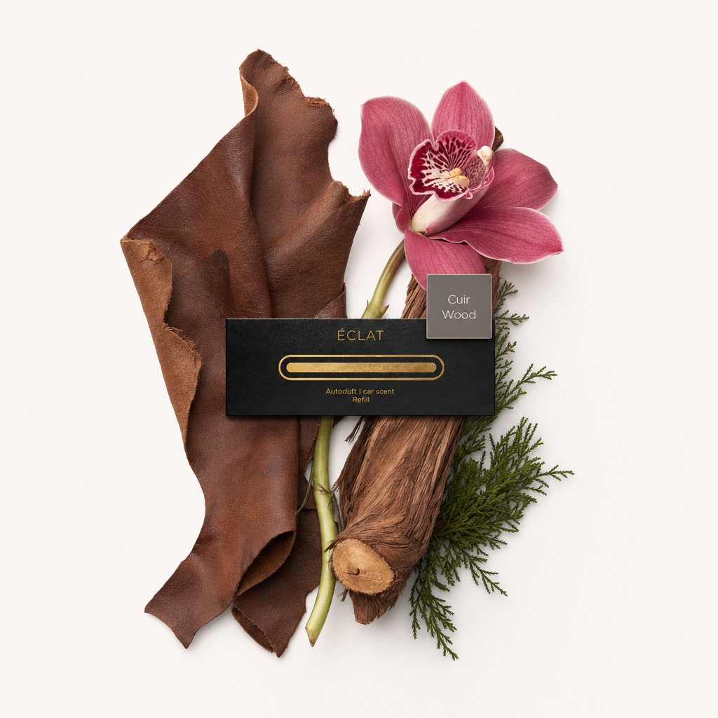 Ein Arrangement aus Lederstücken, einer pinken Orchidee, Holzelementen und Koniferensprossen umgibt ein schwarzes Etikett mit ÉCLAT-Logo.