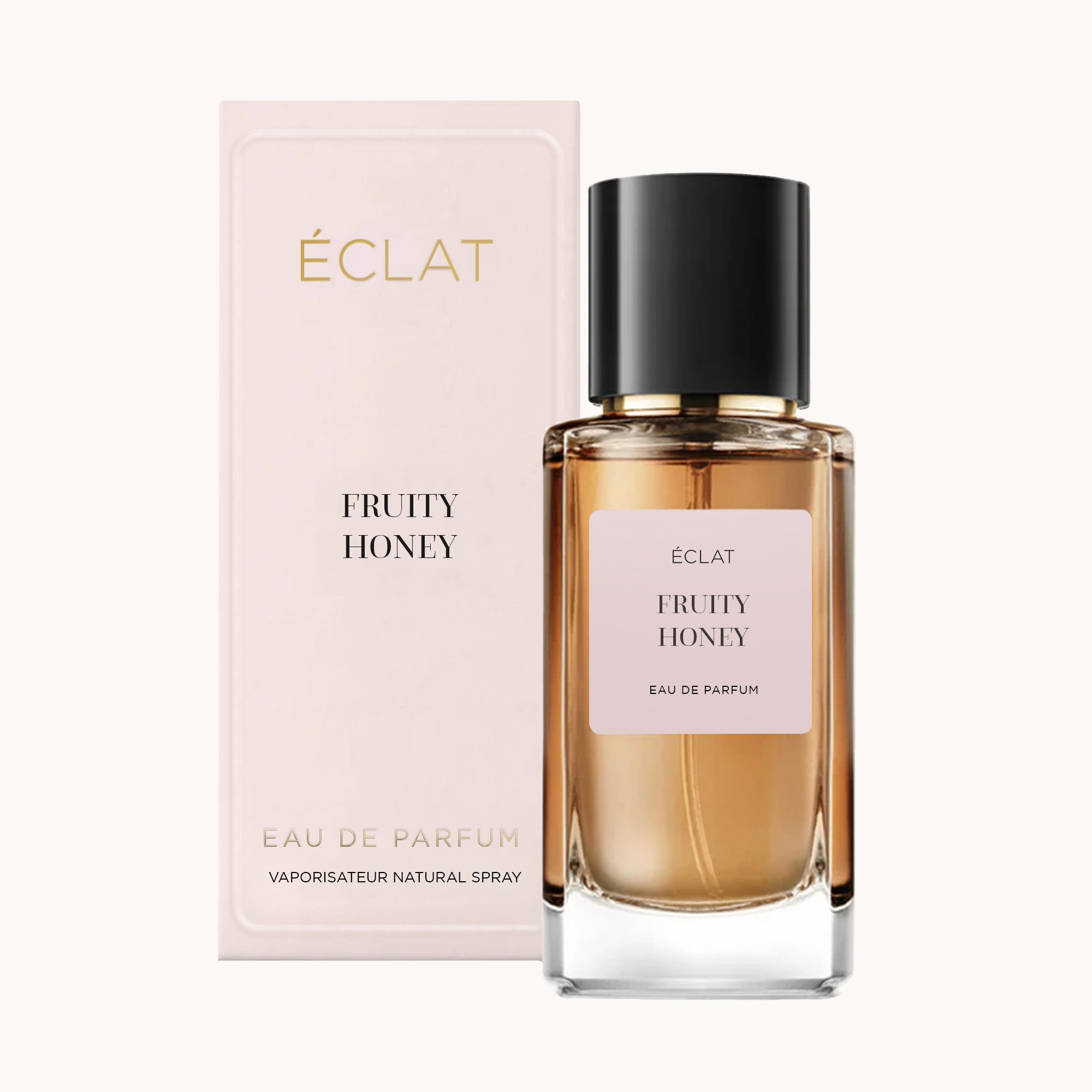Ein facettierter Glasflakon ÉCLAT Fruity Honey mit schwarzer Kappe, vor einer zartrosa Verpackungsbox platziert.