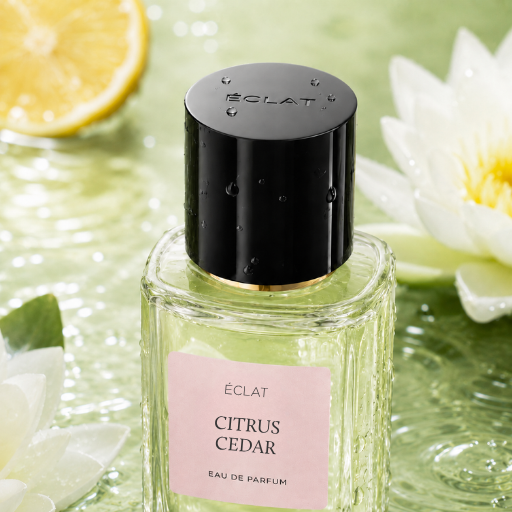 Facettierter Glasflakon von ÉCLAT Citrus Cedar mit schwarzem Verschluss auf Wasserfläche mit Zitronenscheibe und weißen Blüten.