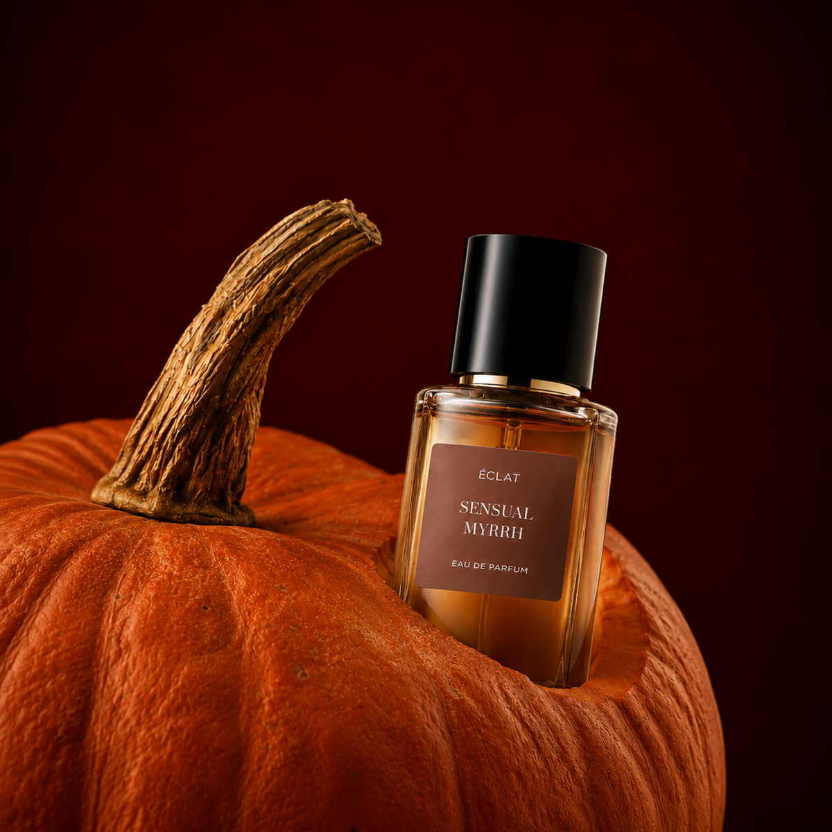 Der ÉCLAT Sensual Myrrh Flakon ruht elegant in einem geschnitzten Kürbis vor tiefrotem Hintergrund.
