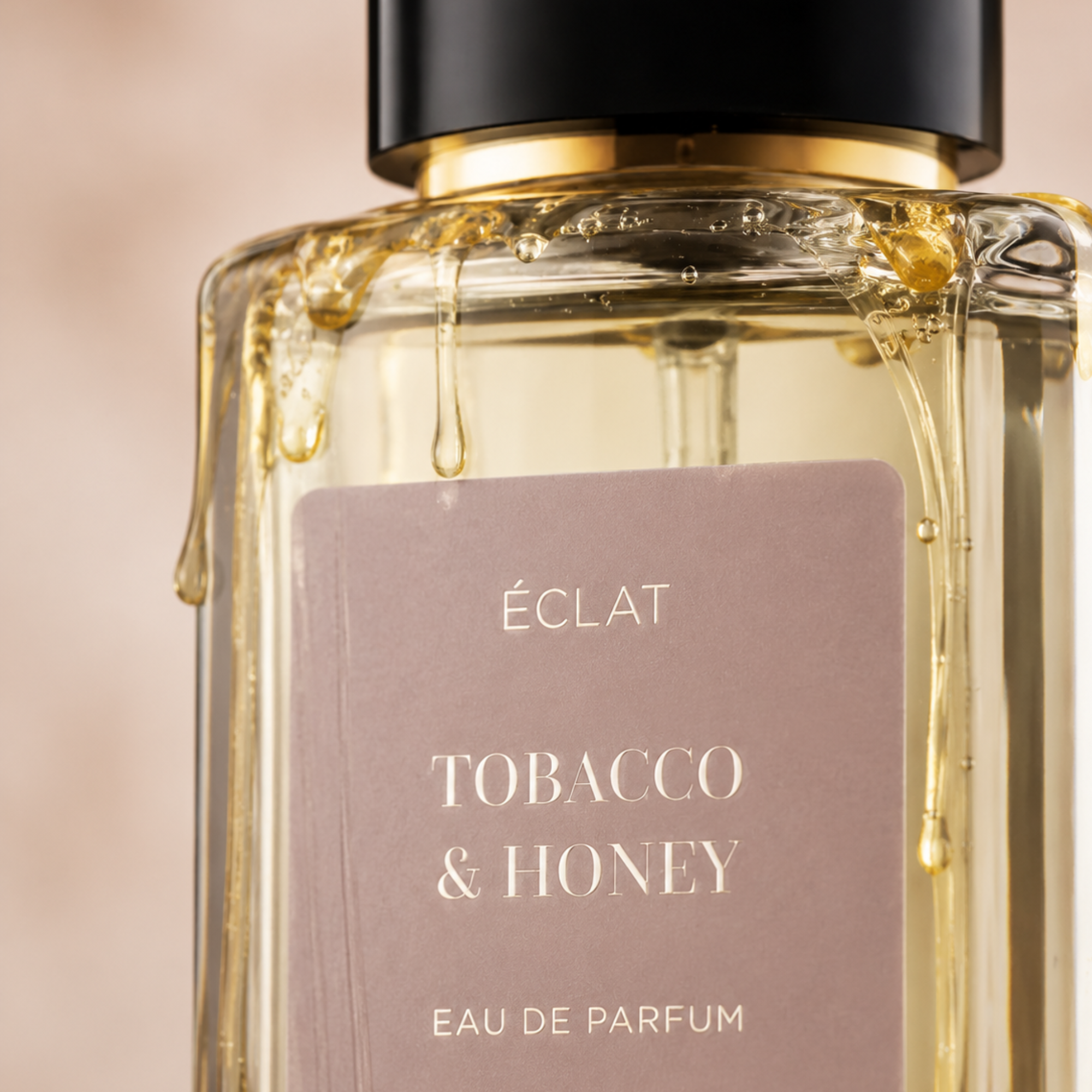 Ein facettierter Glasflakon von ÉCLAT Tobacco & Honey mit satiniertem Etikett und schwarzem Verschluss, verziert mit Honigtropfen.