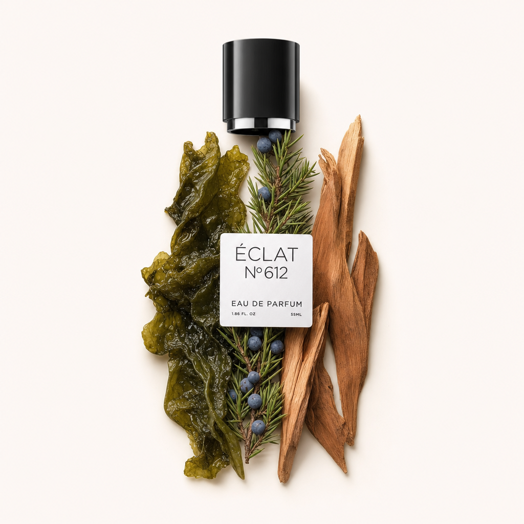 Eine schwarze Verschlusskappe mit Etikett von ÉCLAT Aquatic Cedar liegt inmitten eines Arrangements aus grünem Seetang, Wacholderbeeren und Zedernholzspänen.