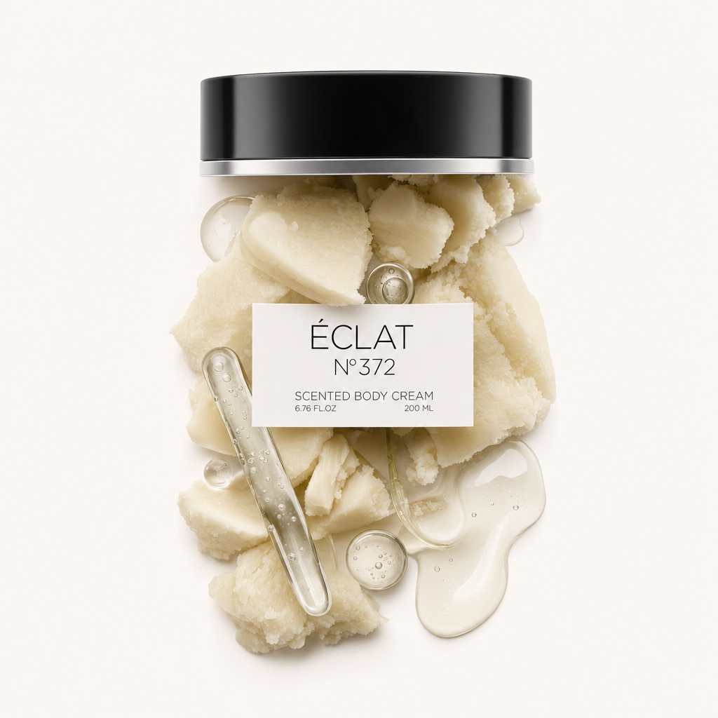 Arrangement aus cremiger Body-Cream-Textur und glänzenden Tropfen um eine schwarze ÉCLAT-Kappe mit Etikett.