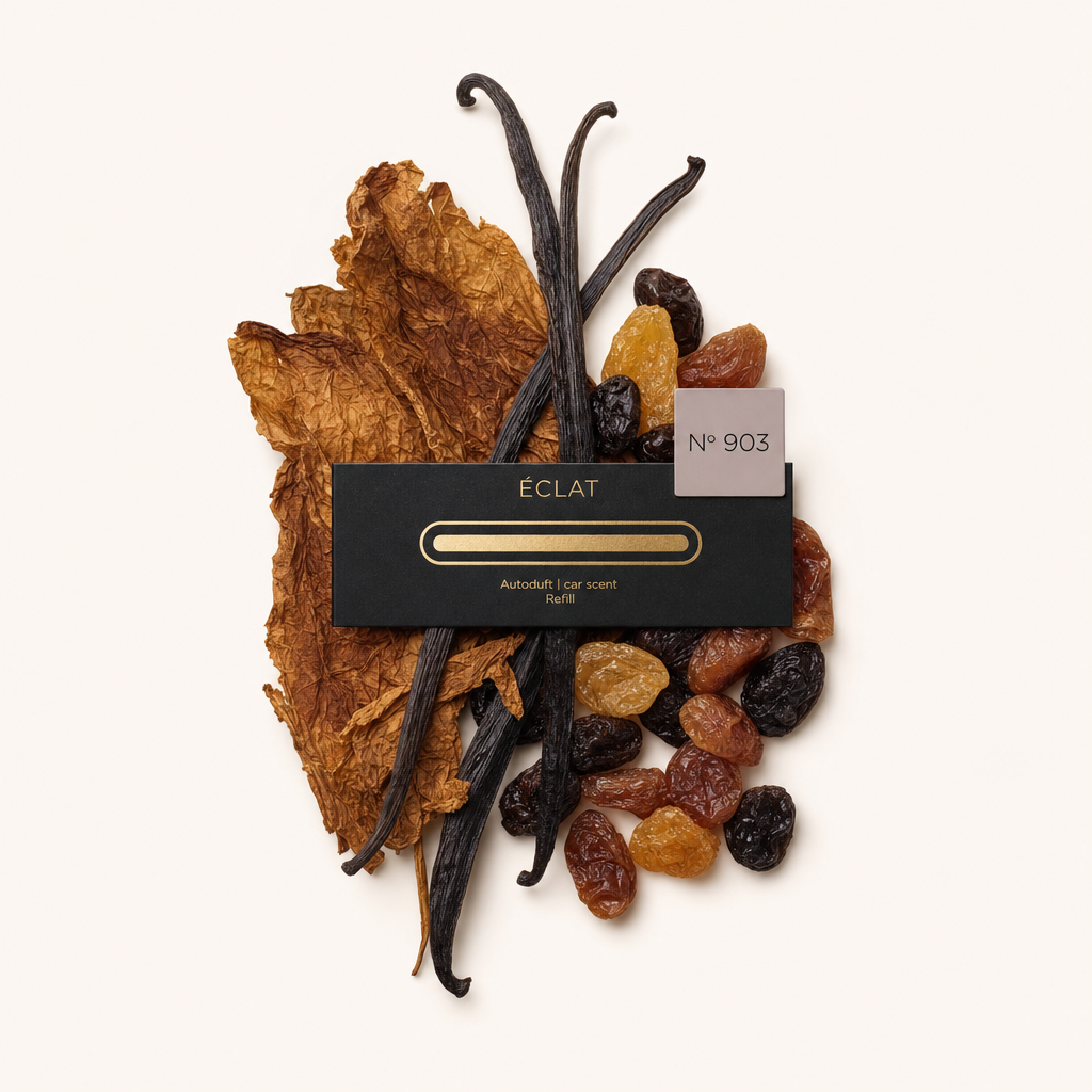 Ein Arrangement aus getrockneten Tabakblättern, Vanilleschoten und verschiedenen Rosinen umgibt eine schwarze ÉCLAT-Kappe mit der Aufschrift Nr. 903.