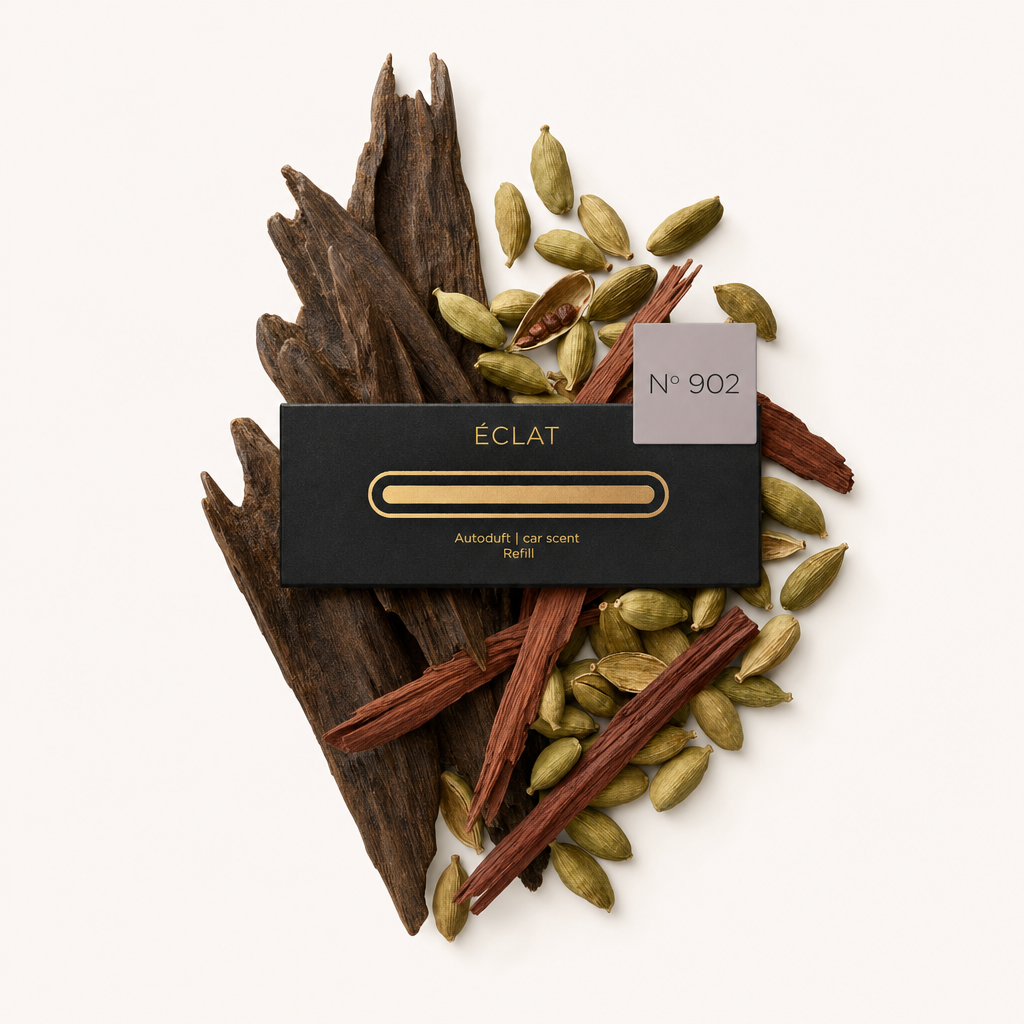 Ein Arrangement aus Kardamomkapseln und aromatischen Hölzern umgibt eine schwarze ÉCLAT-Kappe mit einem Etikett mit der Aufschrift Nr. 902.
