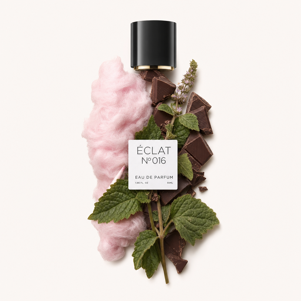 Ein Arrangement aus rosa Zuckerwatte, Schokoladenstücken und grünen Patchouli-Blättern umgibt eine schwarze Kappe mit Etikett und repräsentiert ÉCLAT Cotton Candy & Patchouli.