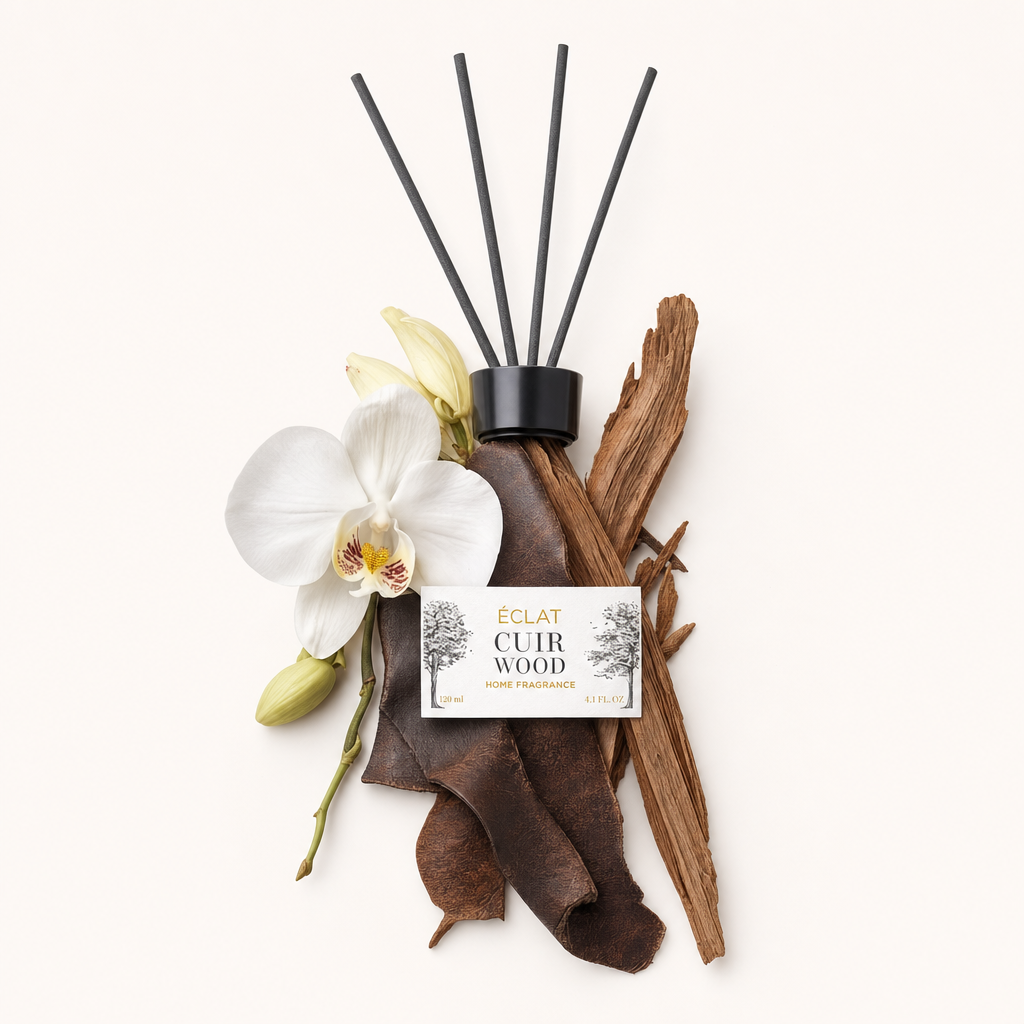 Kunstvoll arrangierte Zutaten von ÉCLAT Cuir Wood, mit einer Orchidee, Leder und Holzstücken neben der schwarzen Kappe mit Etikett.