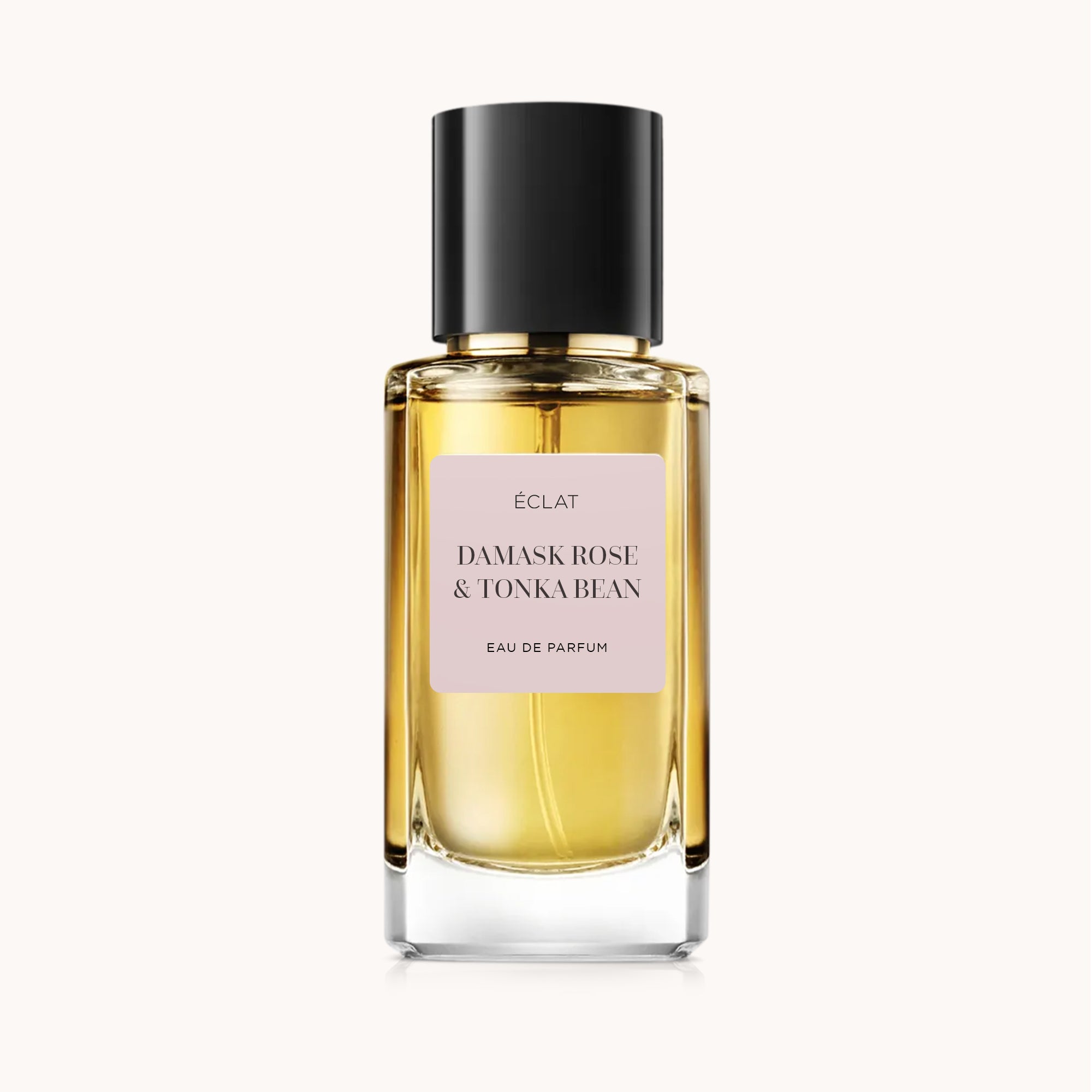 Facettierter Glasflakon mit goldenem Schimmer und mattschwarzer Kappe, mit rosa Etikett von ÉCLAT Damask Rose & Tonka Bean.