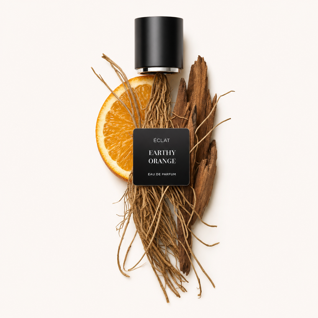 Ein Arrangement aus erdigen Wurzeln, einer Orangenscheibe und Holzstücken unter einem schwarzen Verschluss mit ÉCLAT Earthy Orange Etikett.