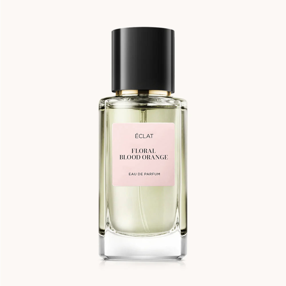 Ein facettierter Glasflakon mit schwarzem Verschluss und rosa Etikett für ÉCLAT Floral Blood Orange Parfum.