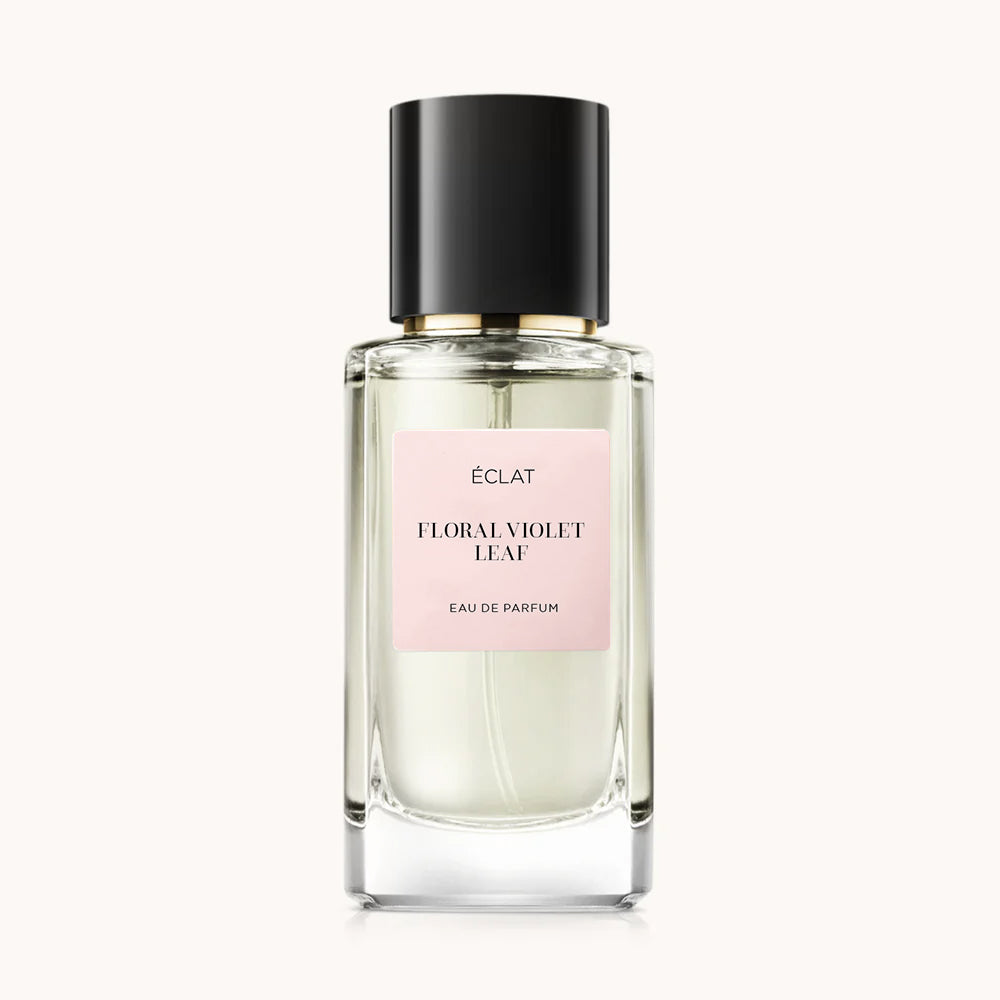 Eleganter Glasflakon mit schwarzem Verschluss und blassrosa Etikett des ÉCLAT Floral Violet Leaf Parfums.