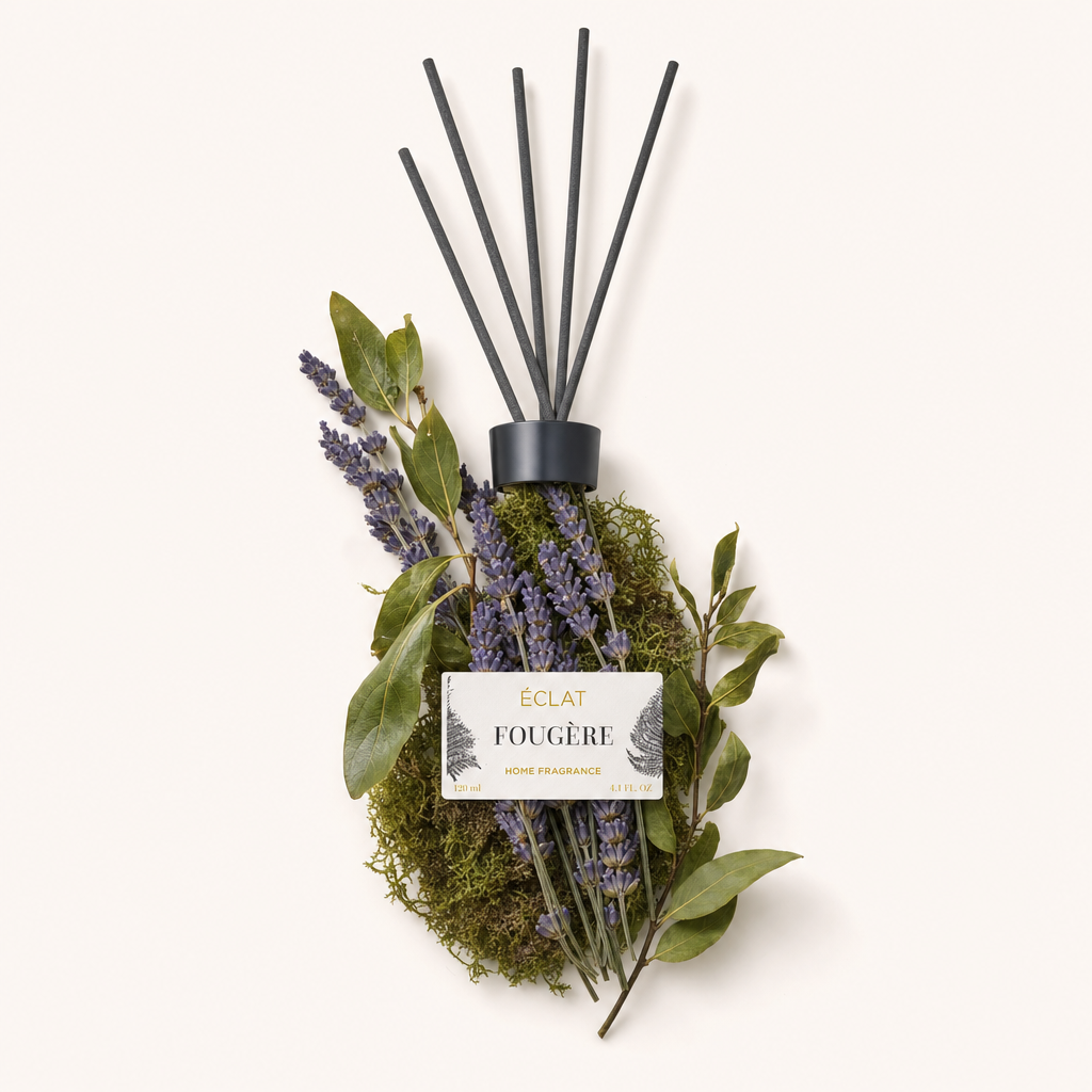 Ein Arrangement aus Lavendel und grünen Blättern um eine schwarze Kappe mit Etikett, das den ÉCLAT Fougère Raumduft hervorhebt.