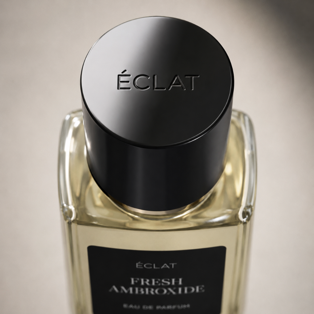 Ein facettierter Glasflakon von ÉCLAT Fresh Ambroxide mit einer eleganten schwarzen Kappe und einem matten Etikett vor neutralem Hintergrund.