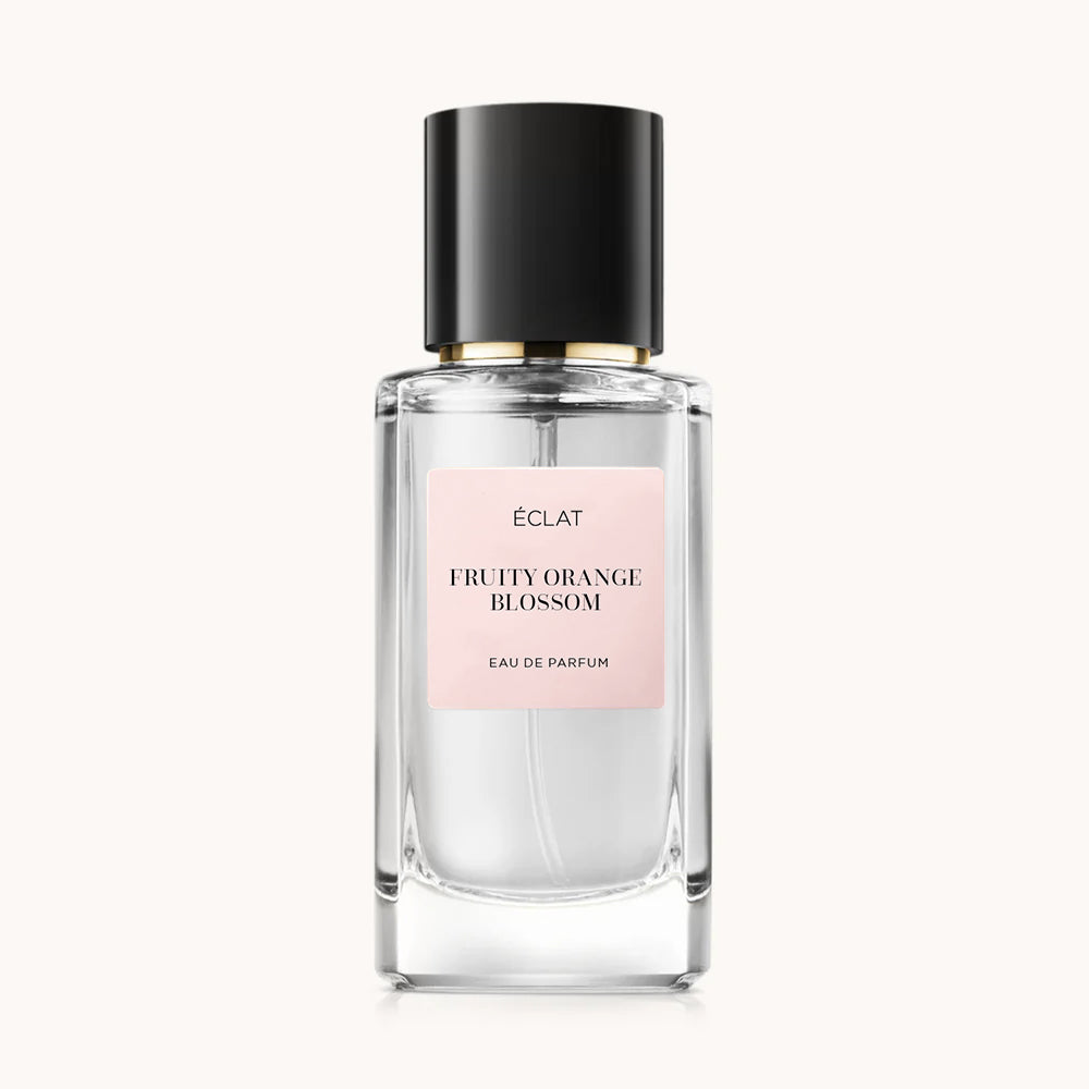 Ein facettierter Glasflakon mit schwarzem Verschluss und rosa Etikett für ÉCLAT Fruity Orange Blossom.