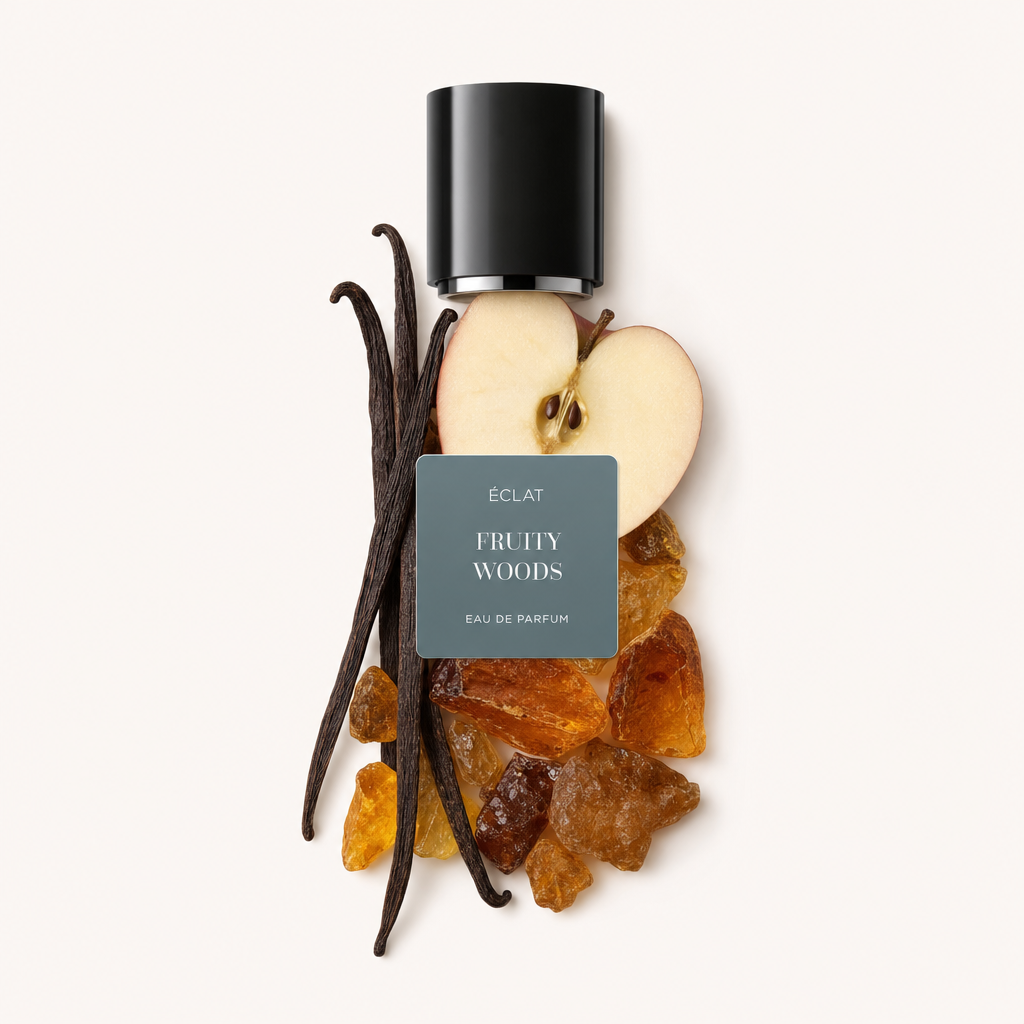Ein Arrangement aus einer Apfelscheibe, Vanilleschoten und Harzen, gekrönt von einer schwarzen Kappe mit ÉCLAT Fruity Woods Etikett.