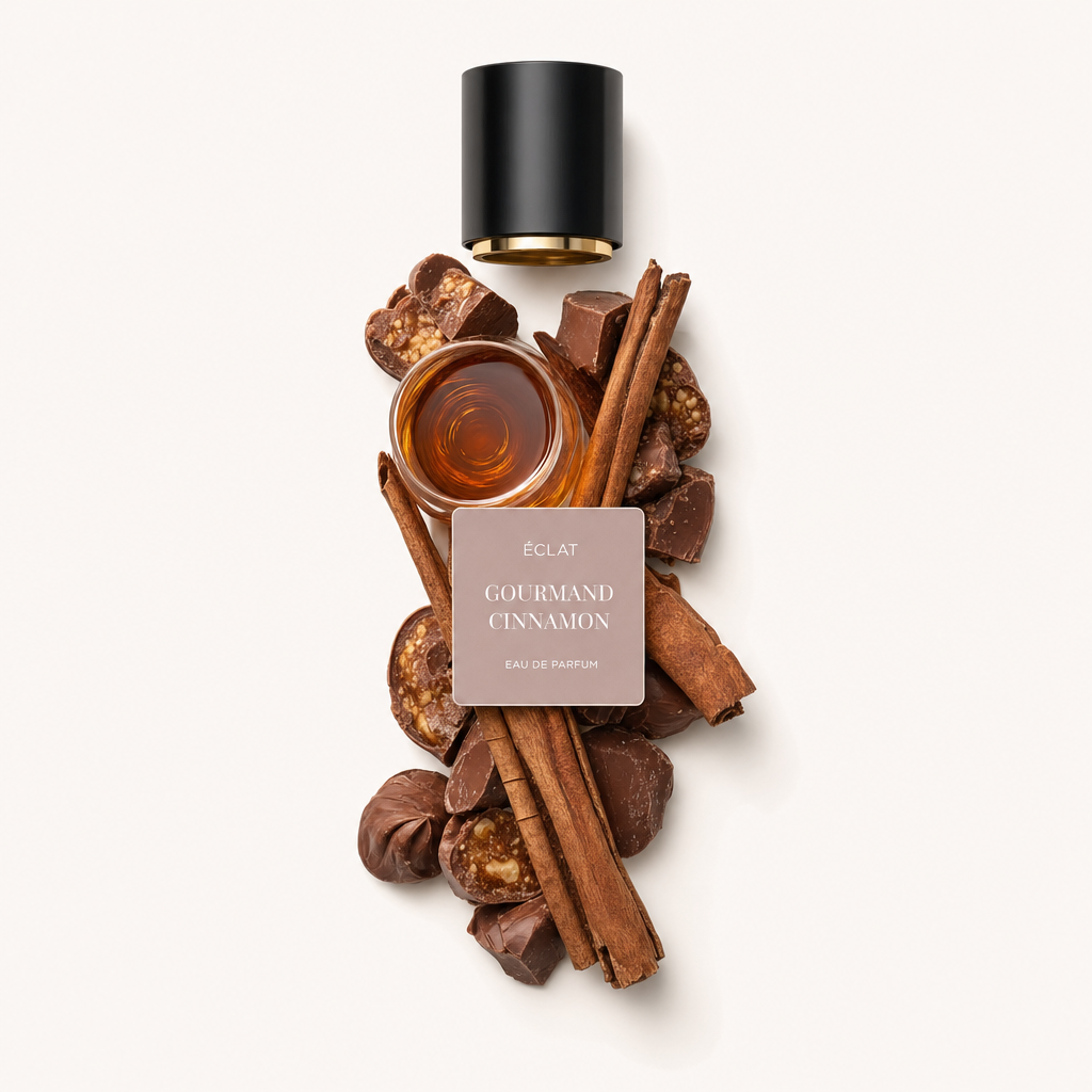 Ein sorgfältig arrangiertes Stillleben von ÉCLAT Gourmand Cinnamon zeigt Zimtstangen, Schokoladenstücke und Nüsse um eine kleine Glasschale mit Flüssigkeit. Die Komposition wird von einer schwarzen Kappe mit Etikett gekrönt.