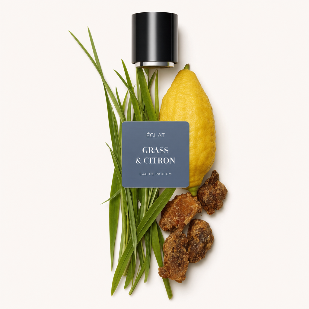 Ein Arrangement aus Grashalmen, einer ganzen Zitrone und Harzstücken präsentiert sich mit einer schwarzen Verschlusskappe und einem Etikett von ÉCLAT Grass & Citron.