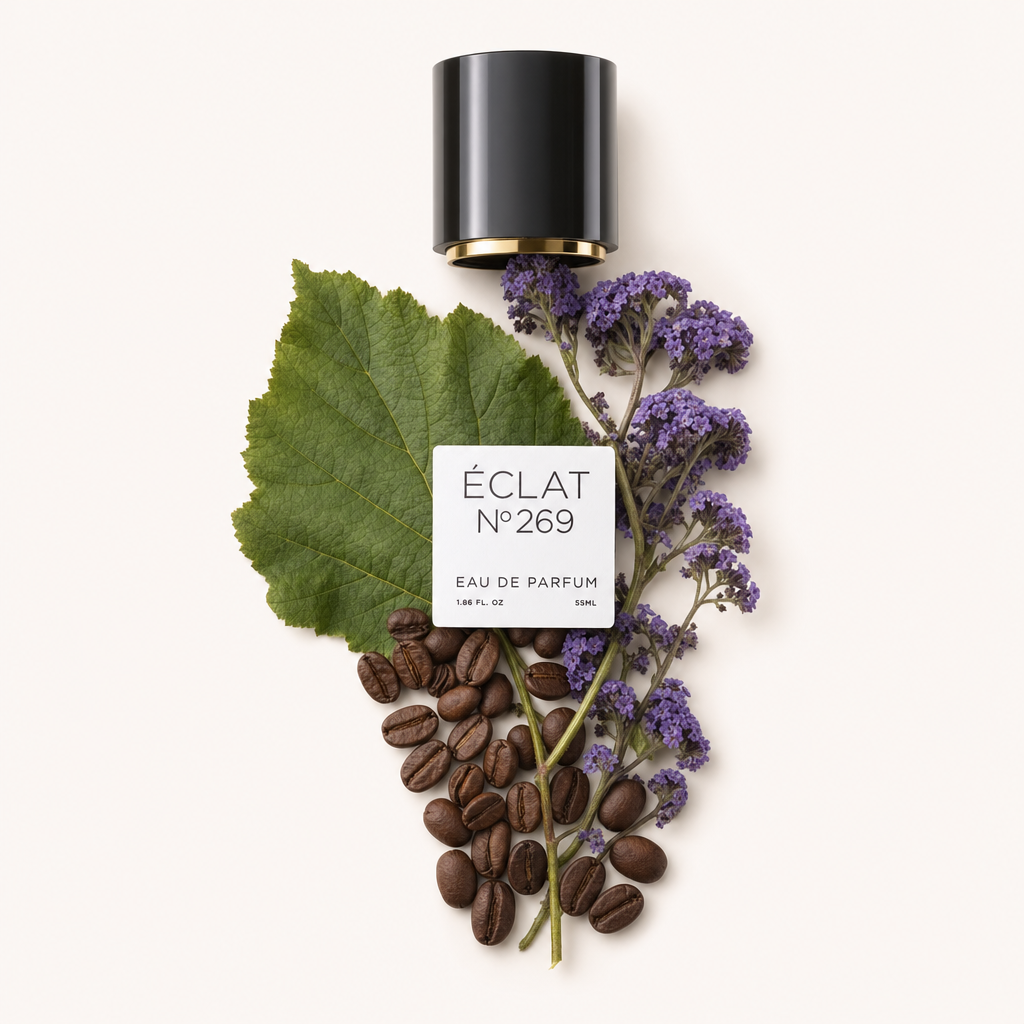 Ein Arrangement aus Kaffeebohnen, großen grünen Blättern und violetten Heliotrop-Blüten umgibt eine schwarze zylindrische Kappe mit einem Etikett, das ÉCLAT Heliotrope & Coffee zeigt.