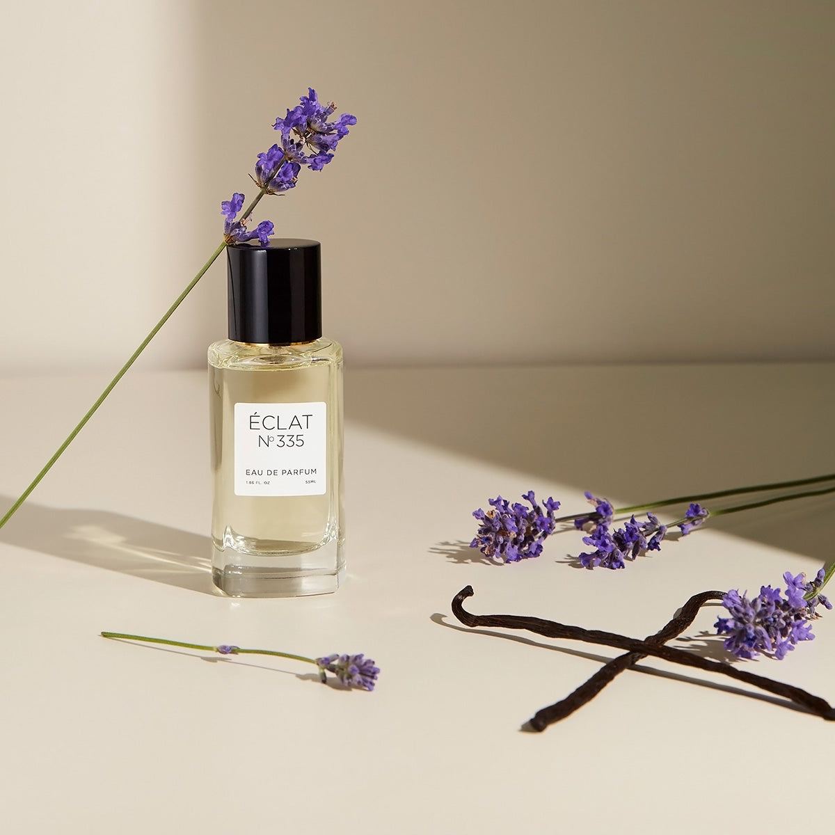 Facettierter Glasflakon von ÉCLAT Lavender & Vanilla mit schwarzem Verschluss, umgeben von Lavendelzweigen und Vanilleschoten.