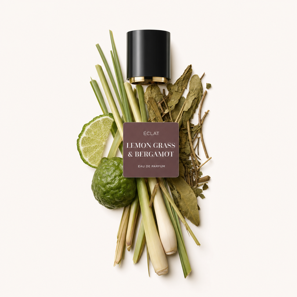 Ein Arrangement aus Zitronengrasstängeln, Kaffirlimettenblättern, Limettenscheiben und ganzer Bergamotte, neben einer schwarzen Kappe mit Etikett von ÉCLAT Lemon Grass & Bergamot.