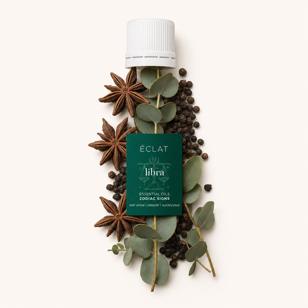 Ein Arrangement aus Sternanis, schwarzen Pfefferkörnern und Eukalyptusblättern umgibt eine weiße Kappe mit ÉCLAT-Zodiac Sign Libra-Etikett.
