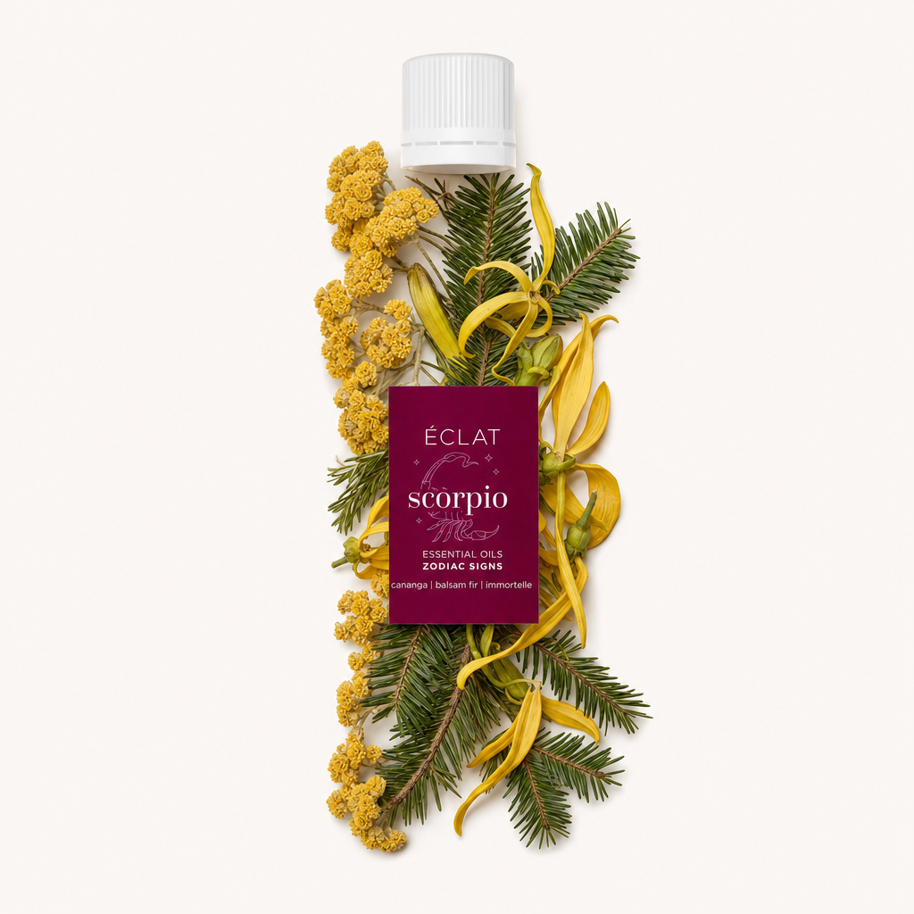 Ein Arrangement aus gelben Ylang-Ylang-Blüten, gelben Immortelle-Blüten und grünen Tannenzweigen umgibt eine schwarze Verschlusskappe mit Etikett von ÉCLATs Scorpio-Zodiac-Sign-Ätherischen-Ölen.