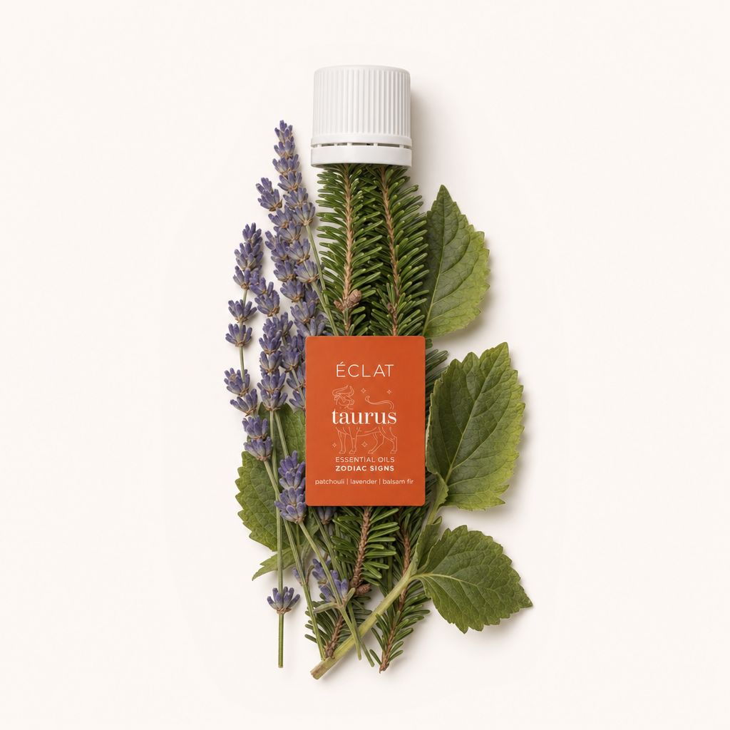 Ein Arrangement aus Lavendelzweigen, Balsamtannenzweigen und Patchouliblättern umgibt eine schwarze Kappe mit orangefarbenem ÉCLAT Taurus Etikett.