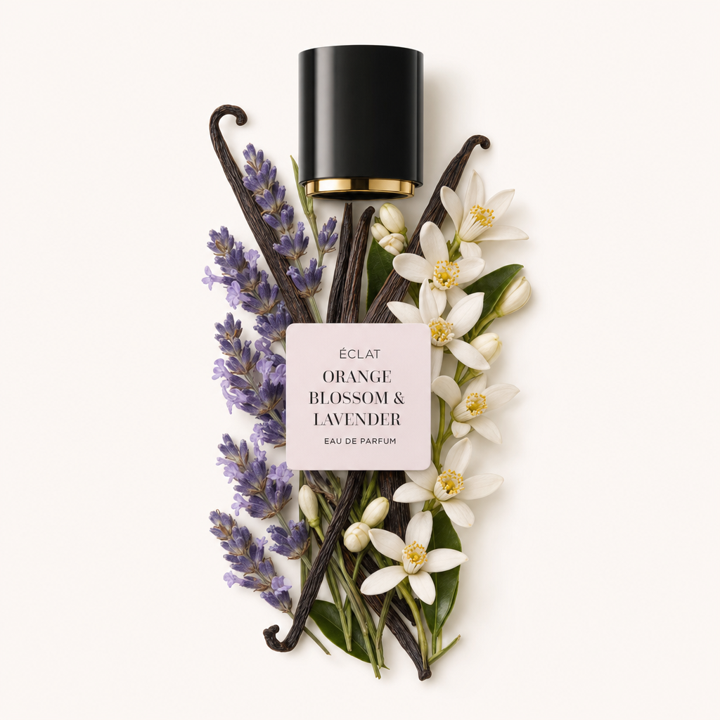 Ein arrangiertes Stillleben aus Lavendel, Orangenblüten und Vanilleschoten. Oben liegt eine schwarze Kappe mit goldfarbenem Innenleben und dem Etikett ÉCLAT Orange Blossom & Lavender.