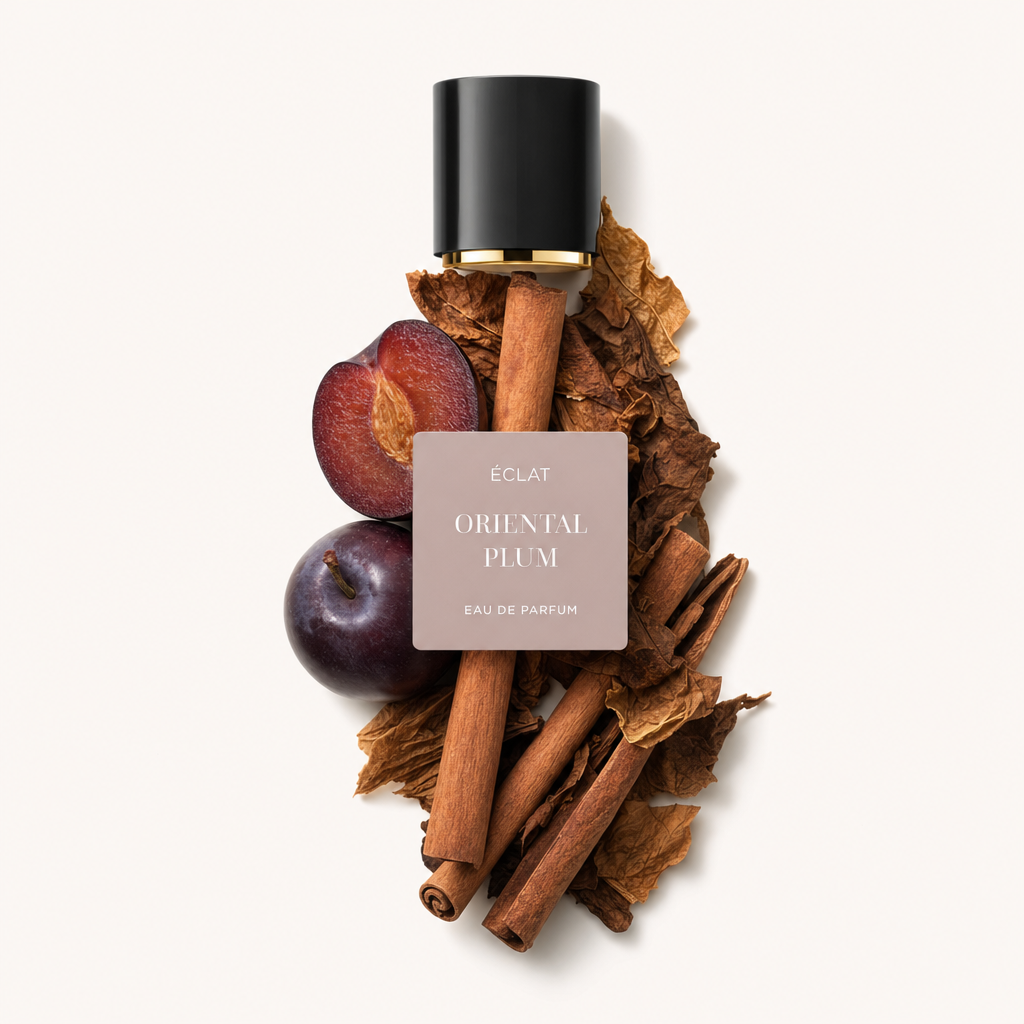 Ein Arrangement aus Zimtstangen, getrockneten Tabakblättern und reifen Pflaumen umgibt eine schwarze Kappe mit goldenen Akzenten, beschriftet mit ÉCLAT Oriental Plum.