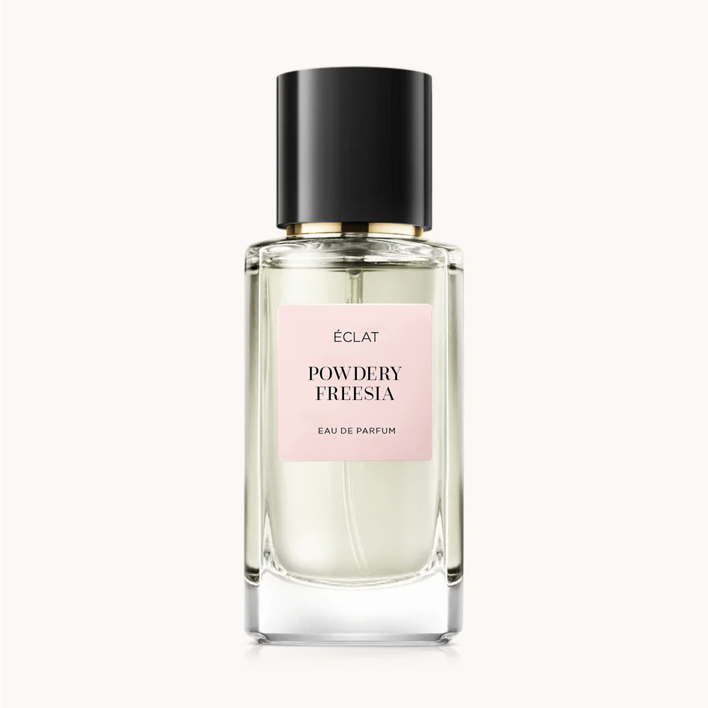 Facettierter Glasflakon von ÉCLAT Powdery Freesia mit schwarzer Kappe und blassrosa Etikett.