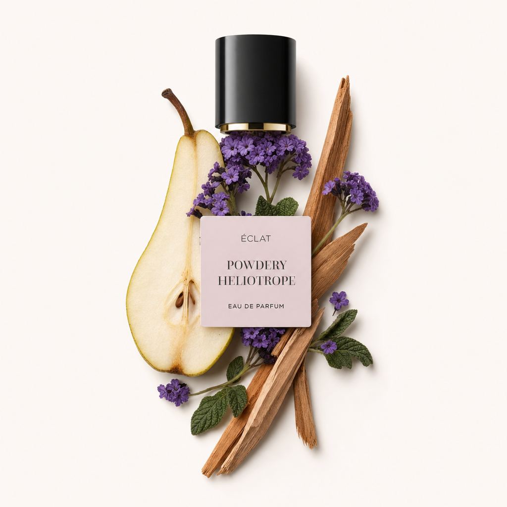Ein Arrangement aus violetten Heliotrop-Blüten, einer aufgeschnittenen Birne, grünen Blättern und Holzstücken umgibt eine schwarze Kappe mit Etikett für ÉCLAT Powdery Heliotrope.