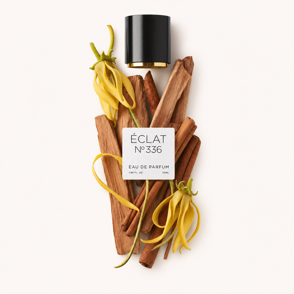 Ein Arrangement aus gelben Ylang-Ylang-Blüten und Sandelholzstäben begleitet eine schwarze Kappe mit Etikett für ÉCLAT Powdery Sandalwood.