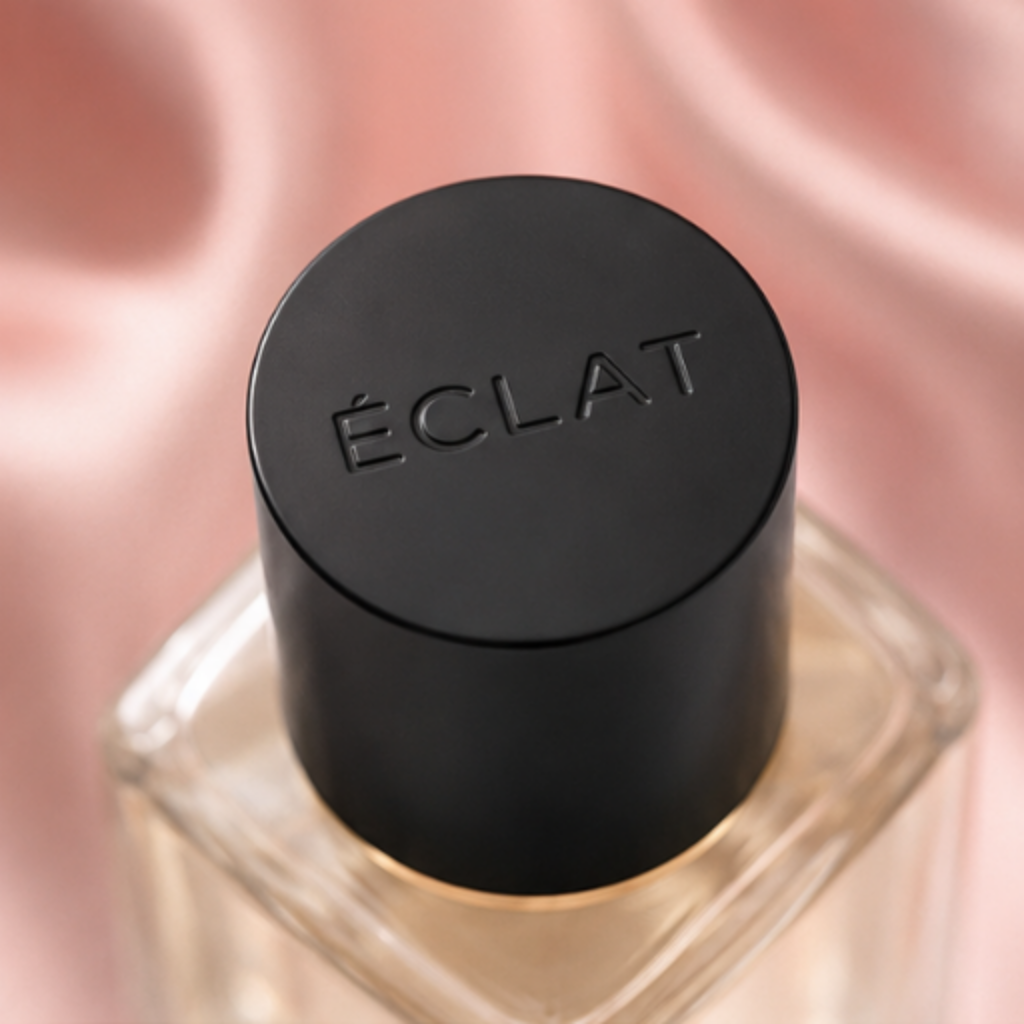 ÉCLAT Silk & Cashmere in einem facettierten Glasflakon mit matter schwarzer Kappe auf einem rosa Satin Hintergrund.
