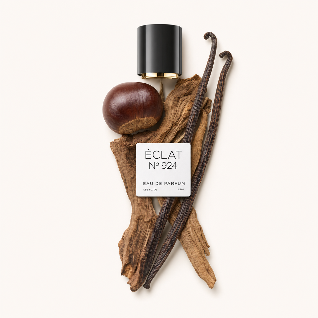 Ein künstlerisches Arrangement von ÉCLAT Smoky Chestnut umfasst eine glänzende schwarze Kappe mit goldfarbenem Akzent, eine ganze Kastanie, duftende Vanilleschoten und strukturierte Holzelemente.