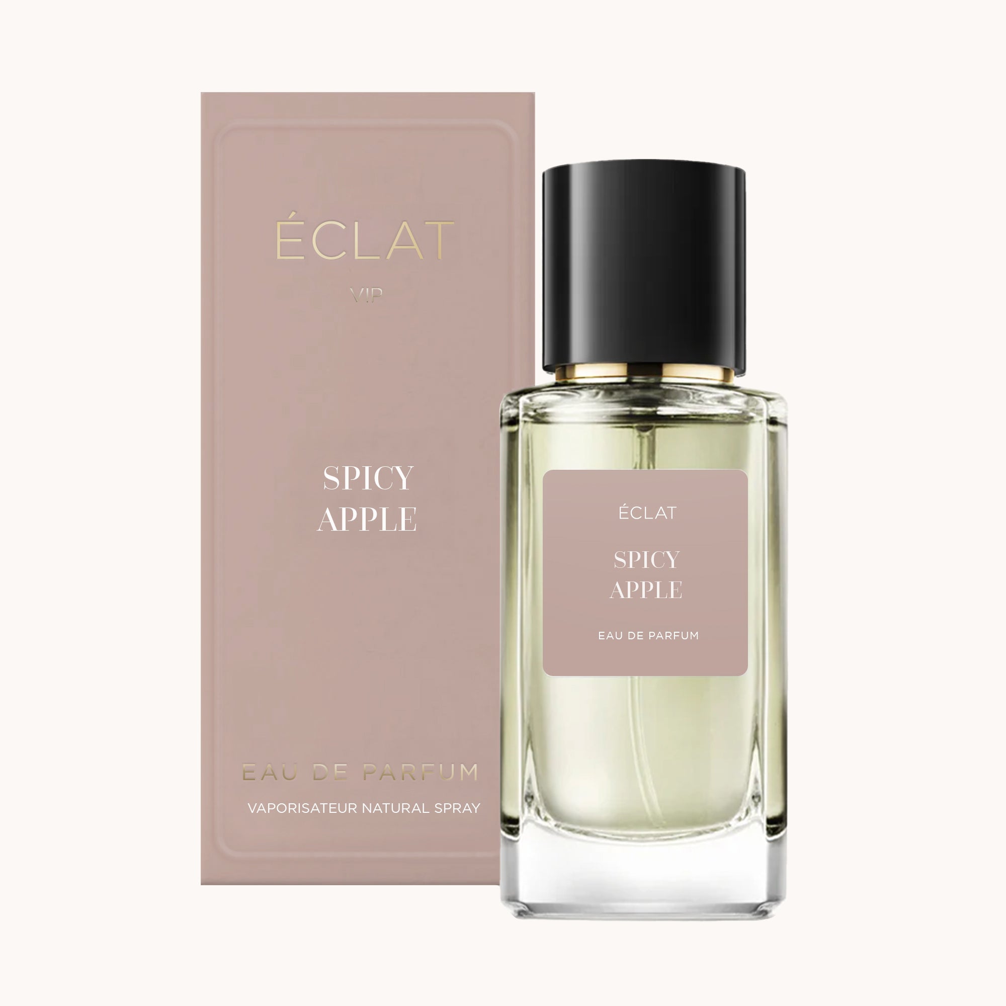 Ein facettierter Glasflakon von ÉCLAT Spicy Apple mit schwarzer Kappe steht neben einer matten Schachtel in gedämpftem Rosa.