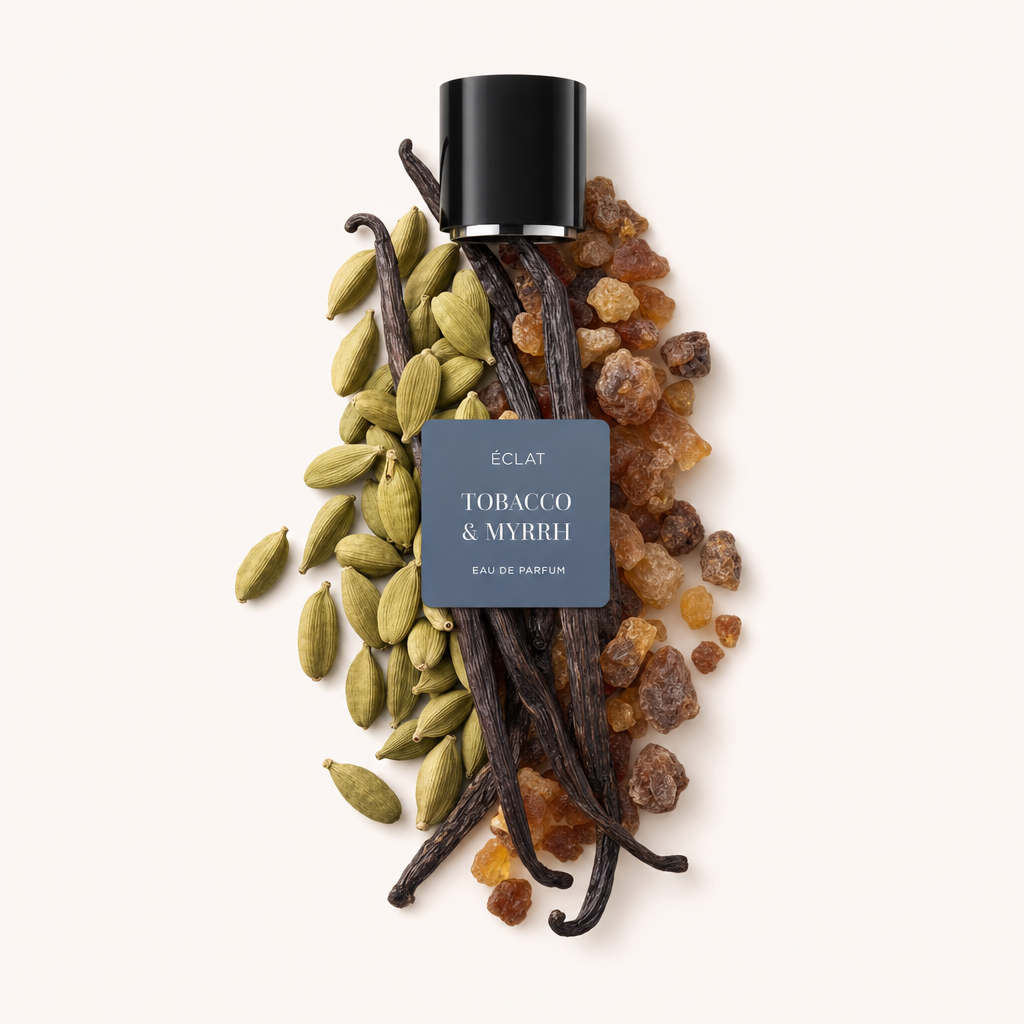 Ein Arrangement aus Kardamomkapseln, Vanilleschoten und Myrrheharz mit einer schwarzen ÉCLAT-Kappe, die 'Tobacco & Myrrh' beschriftet ist, obenauf.