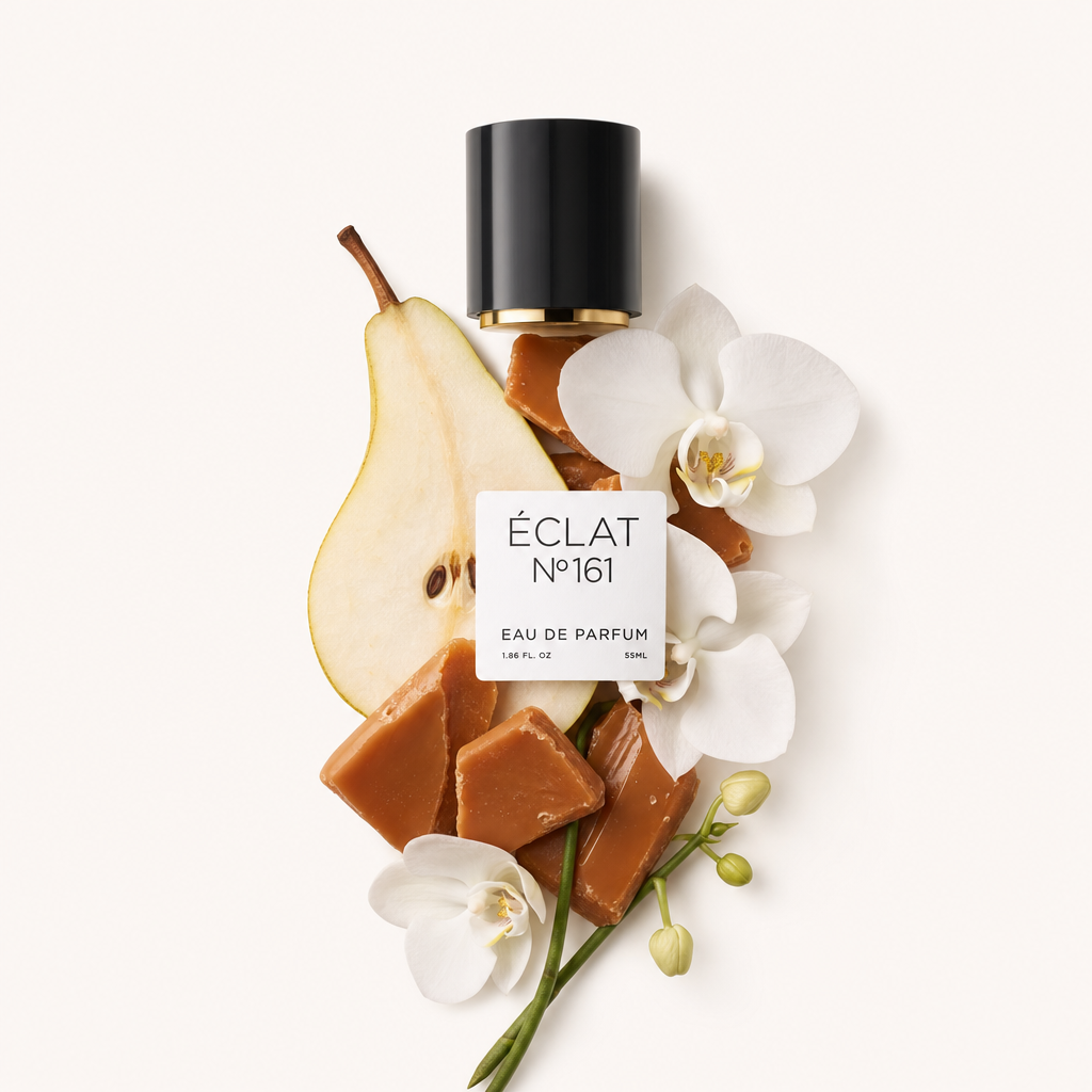 Ein Arrangement aus Toffeestücken, einer Birnenscheibe und weißen Orchideenblüten liegt neben einer schwarzen Kappe mit einem Etikett mit der Aufschrift ÉCLAT Toffee & Patchouli.