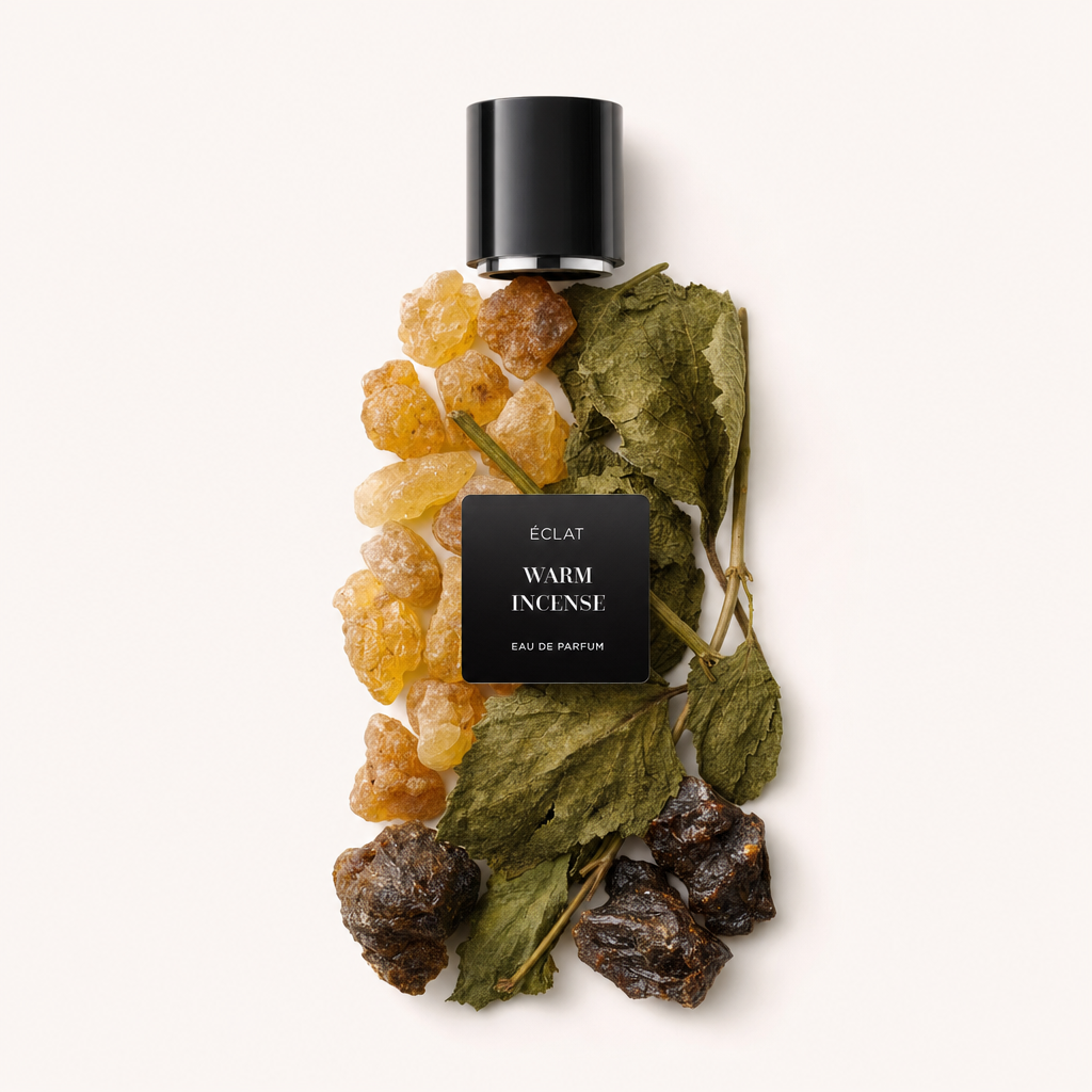 Ein Arrangement aus Bernsteinharz, getrockneten Blättern und dunklen Weihrauchkomponenten, darüber eine schwarze Kappe mit ÉCLAT Warm Incense Etikett.