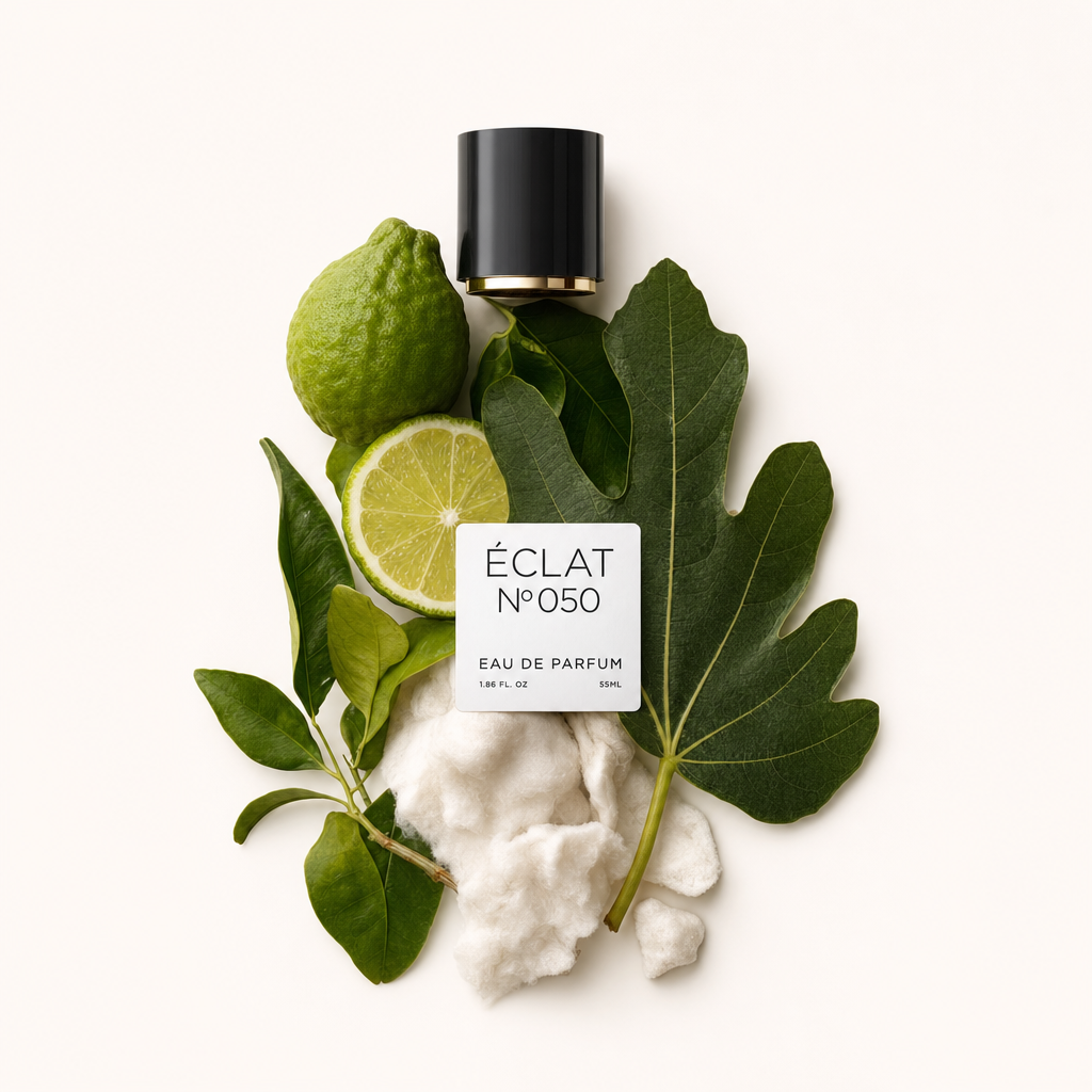 Ein Arrangement aus Zitrusfrüchten, grünen Blättern und weichen weißen Fasern, mit einer schwarzen Kappe mit ÉCLAT White Musk & Citrus Fruits Etikett.