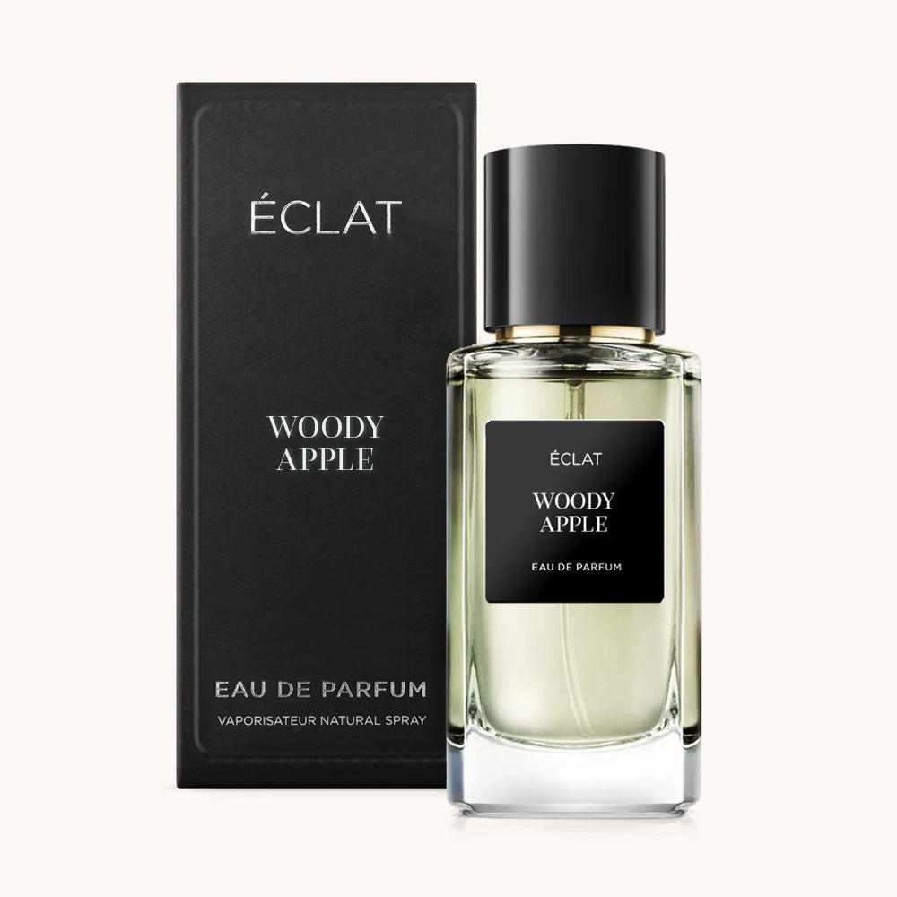 Ein facettierter Glasflakon von ÉCLAT Woody Apple mit schwarzer Kappe, begleitet von der passenden schwarzen Box.