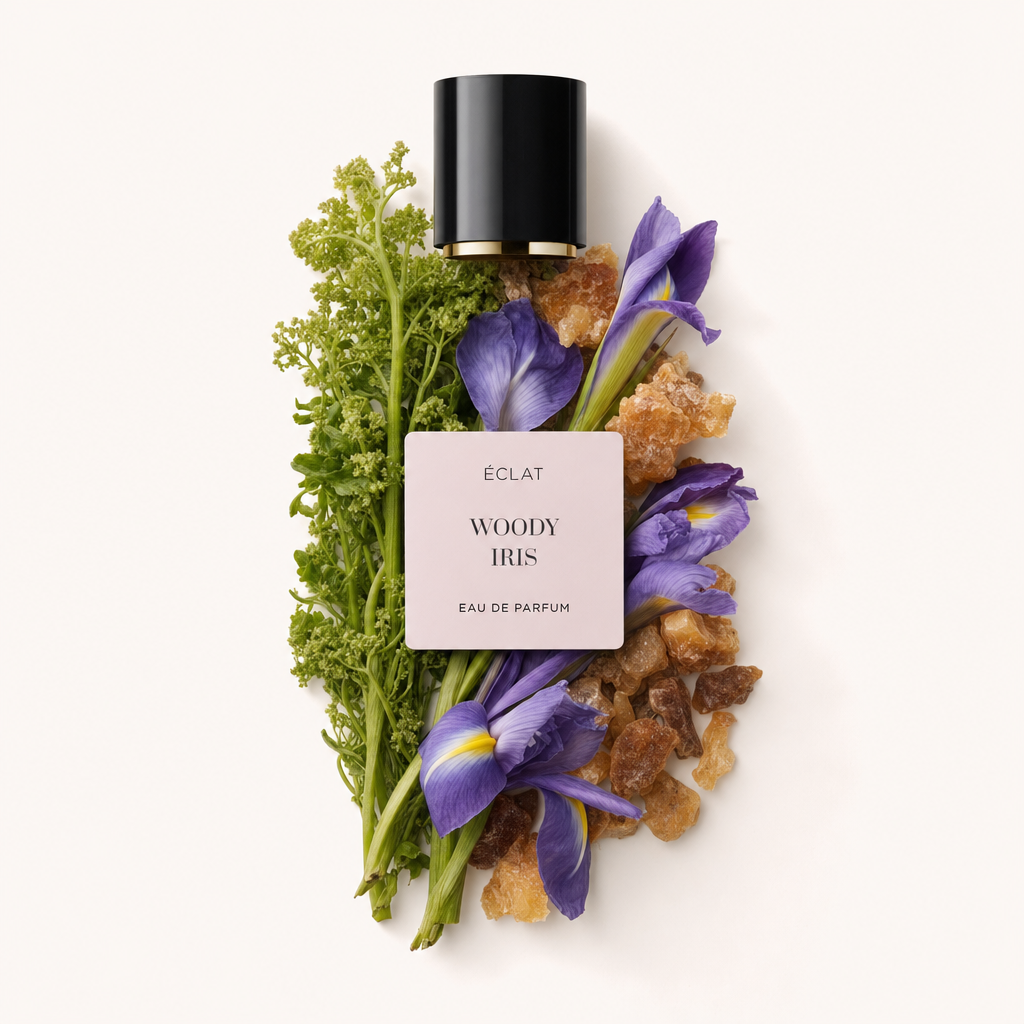 Ein Arrangement aus lebhaften lila Schwertlilien und grünem Laub mit bernsteinartigen Harzstücken umgibt die originale schwarze Kappe mit Etikett für ÉCLAT Woody Iris.