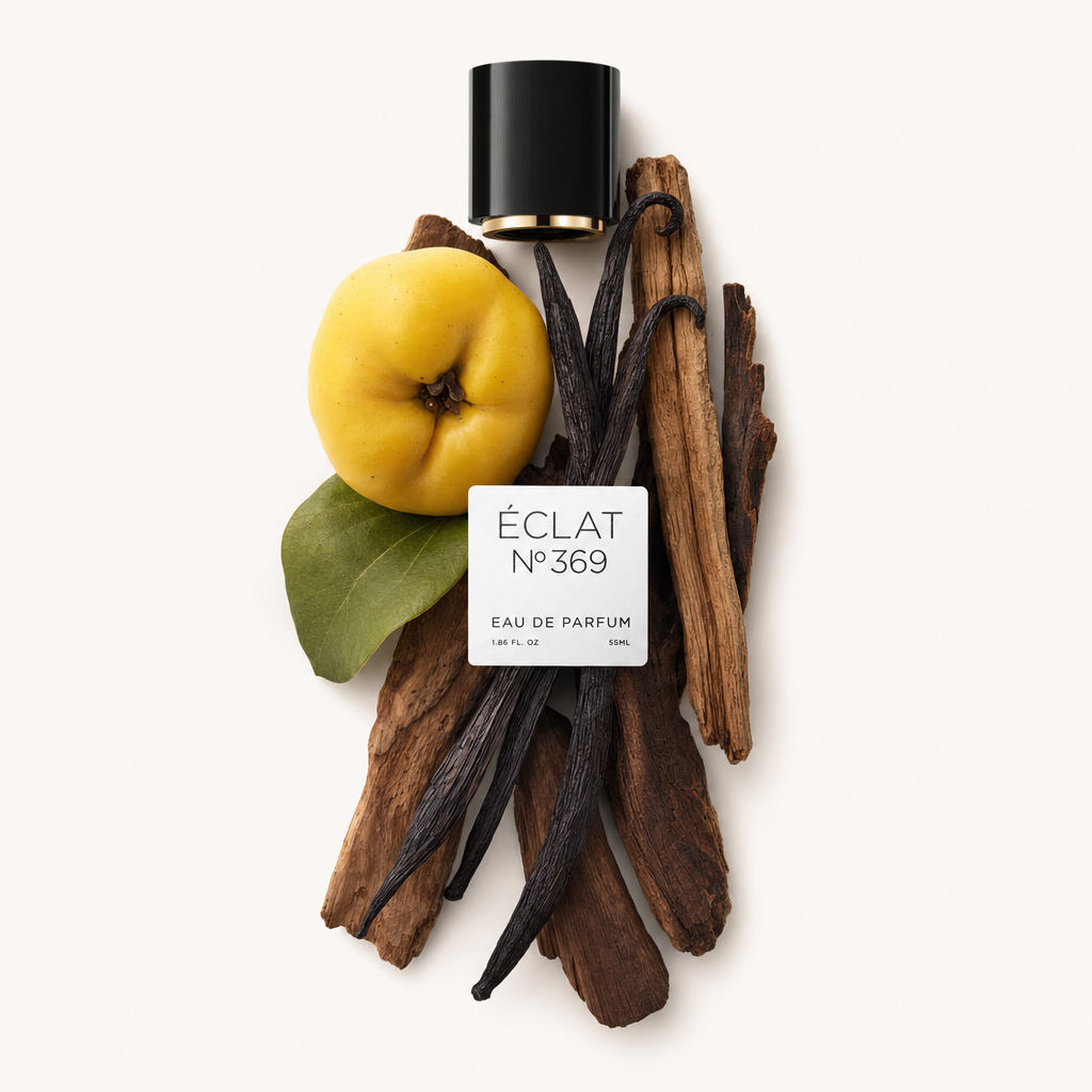 Ein Arrangement aus Vanilleschoten, einer gelben Quitte mit grünem Blatt und Holzstöcken um eine schwarze Kappe mit Etikett von ÉCLAT Woody Vanilla.